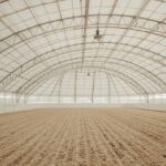 Innenansicht moderne Reithalle mit Sandboden und Membran-Rundbogen-Decke
