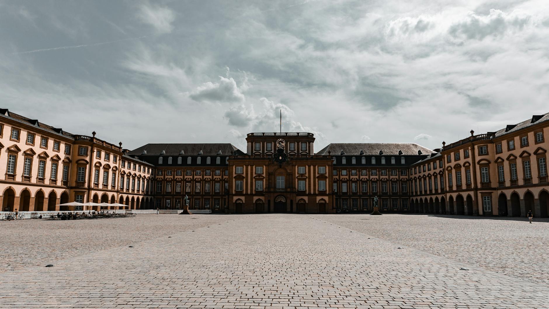 A picturesque courtyard view of Mannheim Palace in Germany showcasing Baroque architecture under a cloudy sky.